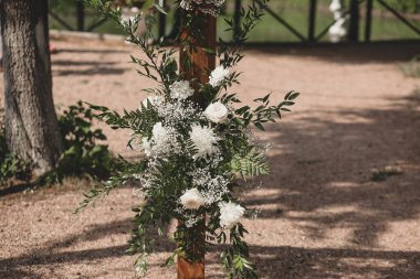 Parkta beyaz çiçeklerle boho tarzında düğün kemeri.