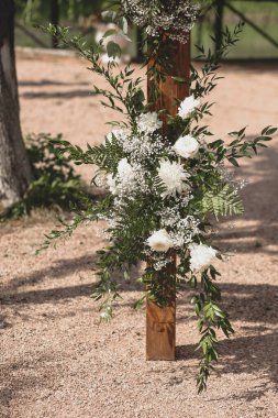Parkta beyaz çiçeklerle boho tarzında düğün kemeri.