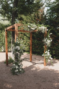 Parkta beyaz çiçeklerle boho tarzında düğün kemeri.