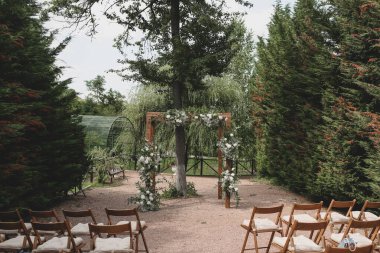 Parkta beyaz çiçeklerle boho tarzında düğün kemeri.