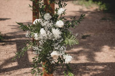 Parkta beyaz çiçeklerle boho tarzında düğün kemeri.