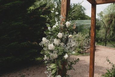 Parkta beyaz çiçeklerle boho tarzında düğün kemeri.