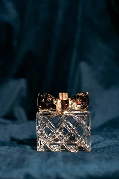 Butelka Pachnących Perfum Kobiet Ciemnoniebieskim Tle Tkaniny Tło Fałdami Kroplami — Zdjęcie stockowe