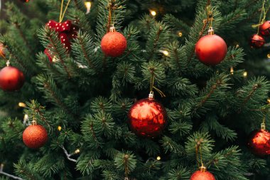 Outdoors image of beautiful decorated christmas tree. Christmas tree branches with balls, christmas tree toy and festive lights with sparkles. Christmas decoration. New Year.