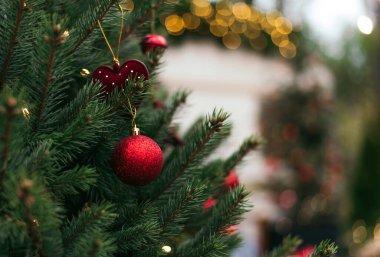 Noel ağacını süsleyen yakın plan. Kırmızı toplar ve el feneriyle süslenmiş çelenkler. Yeni yılın makro fotoğrafları yanında. Kış tatili hafif süslemeleri. Boşluğu kopyala.