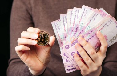 Bir altın sikke bitcoin gösterir - kripto para sembolü, yeni sanal para ve bir yığın Ukrayna Hryvnia parası, seçici odak, ton.