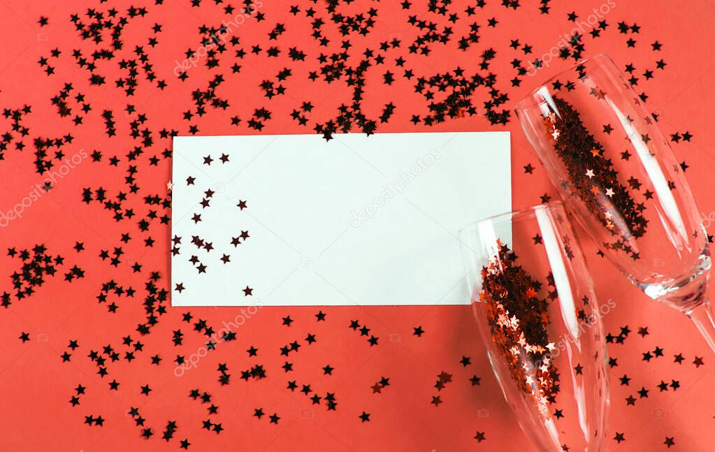 Champagne glass with star shaped sequins on a red background with card blank. Party, christmas, new year and valentine's day celebration concept. banner. Top view. Flat lay