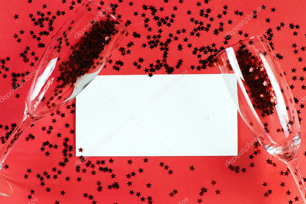 Champagne glass with star shaped sequins on a red background with card blank. Party, christmas, new year and valentine's day celebration concept. banner. Top view. Flat lay