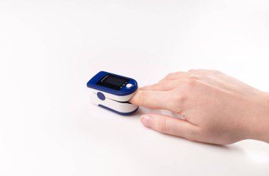 Pulse oximeter used to measure pulse rate and oxygen levels . Close up of Finger in an Oximeter Device. Pulse oximeter on white background clipart