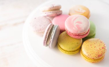 Çok renkli badem kurabiyeleri ahşap arka planda yumuşak ışıklarla kaplanır. Sabah kahvaltısı için nefis Fransız tatlıları..