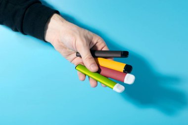 Tek kullanımlık elektronik sigaralar, gölgeli mavi arka planda yakın plan çekimde. Modern sigara, buhar ve nikotin kavramı. Boşluğu kopyala.