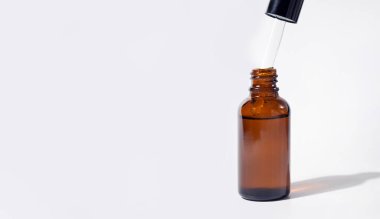 Yağ damlalı kozmetik pipet ya da gölgeli serum. Şeffaf kahverengi şişe. Yakın çekim, kopyalama alanı, afiş. Gri arka plan. Sağlık, cilt, vücut bakımı. Aromaterapi