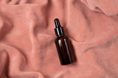 Pembe kumaş kaplamalı kahverengi damlacıklı cam şişeler. Sıfır atık cam kap. Serum, yağ, asit, losyon. Organik, doğal kozmetik. Güzellik, cilt bakımı. Spa ürünleri.