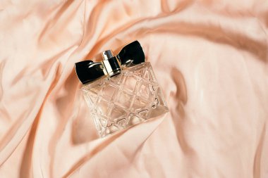 İpek bej arka planda parfüm şişesi. güzellik ve parfüm konsepti.