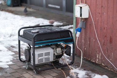 Taşınabilir gaz jeneratörü karlı bir caddede acil güç kaynağı sağlıyor.