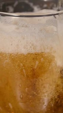 Kalın beyaz köpüklü ve yükselen köpüklü bir bardağa taze altın bira dökülüyor.
