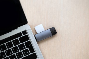 USB-C merkezi, SD kart adaptörüyle ahşap bir masadaki gümüş bir dizüstü bilgisayara bağlı. Modern çalışma alanı teknolojisi