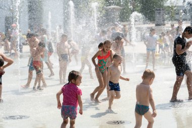 İzhevsk, Rusya - 20 Temmuz 2020: Mutlu çocuklar yaz parkındaki çeşmeye gülüp sıçrıyor. Bir grup çocuk şehir çeşmesinin derelerinde eğleniyor.