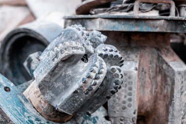 Matkap ucu, sığ alan derinliği ile yakın çekim. Endüstriyel geçmiş. Tricone sondajı paten konisi, bilye ve jet hortumu ile yakın görüntüyü biraz daraltır.