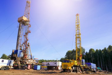 Arka arkaya petrol üreten kuyular var. Arka planda, kuyuyu elden geçirmek için çalışmalar sürüyor. Çeşitli teçhizat ve malzemelerle petrol ve gaz kuyuları açmak için sondaj kulesi.