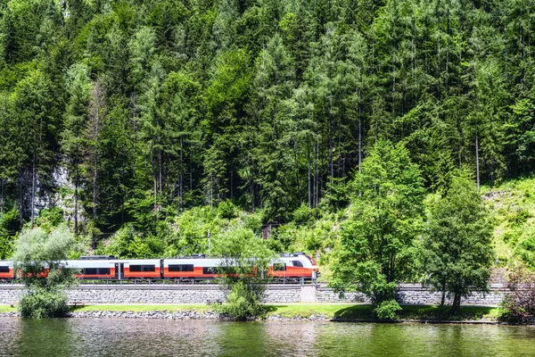 奥地利阿尔卑斯山中的红色蓝色火车开动了 高山高速列车到达高山哈尔斯塔特奥伯特伦火车站 — 图库照片