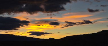 Bulutların arkasına gizlenmiş güneşin batışının manzarası.