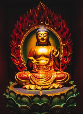 Çin Mahallesi 'ndeki Buda Dişi Kalıntısı Tapınağı. Yakından bakınca, yeşil nilüfer çiçeğinin üzerinde oturan Buda heykelini öğretirken hafifçe gülümserken el işaretleri gösteriyor. Kırmızı alevler arkada..