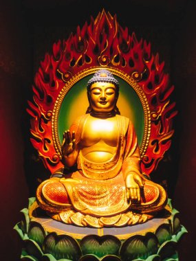 Çin Mahallesi 'ndeki Buda Dişi Kalıntısı Tapınağı. Yakından bakınca, yeşil nilüfer çiçeğinin üzerinde oturan Buda heykelini öğretirken hafifçe gülümserken el işaretleri gösteriyor. Kırmızı alevler arkada..