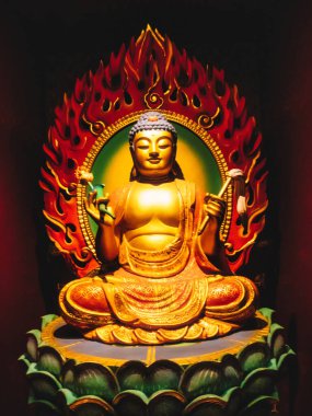 Çin Mahallesi 'ndeki Buda Dişi Kalıntısı Tapınağı. Yakından bakınca, yeşil nilüfer çiçeğinin üzerinde oturan Buda heykelini öğretirken hafifçe gülümserken el işaretleri gösteriyor. Kırmızı alevler arkada..