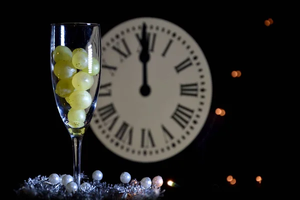 Celebration of the New Year, traditional ritual twelve grapes of luck, view of glass with grapes on clock background