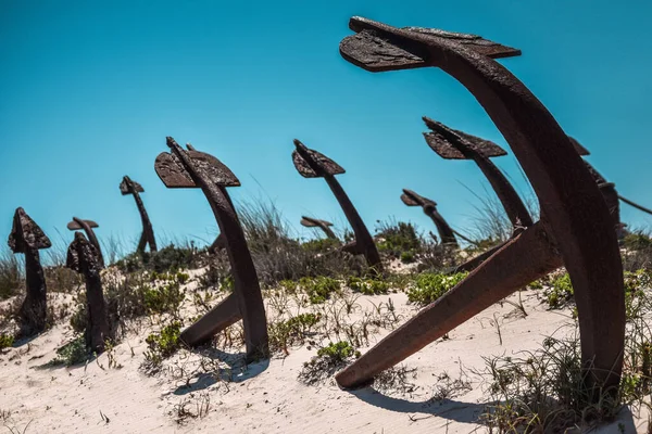 Santa Luzia, Algarve, Portekiz 'deki Praia Do Barril sahilindeki Anchor mezarlığı. Mavi gökyüzü ile kumullarda eski paslı deniz çapaları.
