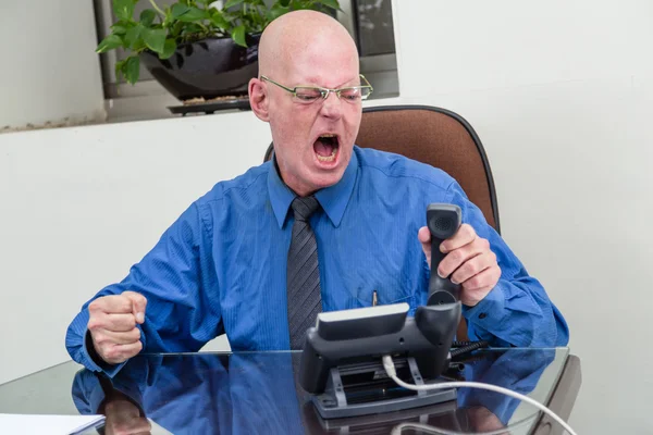 Businessman on phone at desk, angry — Stock Photo, Image