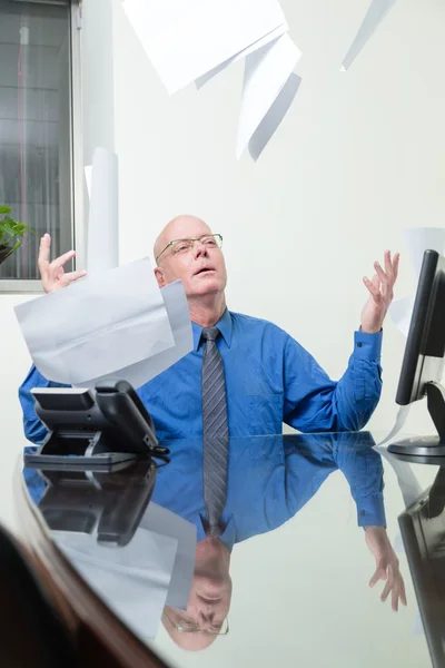 Executive at desk throws papers in air — Stock Photo, Image