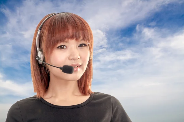 Call center operator with headset and blue sky and clouds in bac — Stock Photo, Image