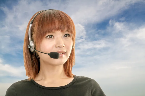 Call center operator with headset and blue sky and clouds in bac — Stock Photo, Image