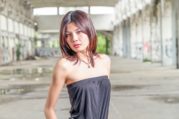 Китаянка стоит в заброшенном здании — стоковое фото