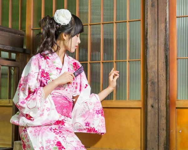 Mujer asiática en kimono sosteniendo ventilador buscando débil — Foto de Stock