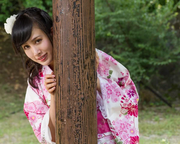 Aziatische vrouw in kimono achter houten pijler — Stockfoto