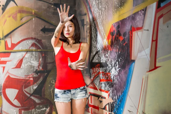 Schöne Chinesin an Graffiti-Wänden mit erhobenen Händen — Stockfoto