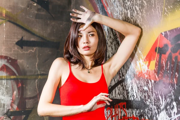 Beautiful Chinese woman by graffiti walls with hands raised — Stock Photo, Image