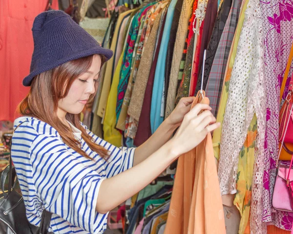 Asian woman looking at clothes on rack — Stock Photo, Image