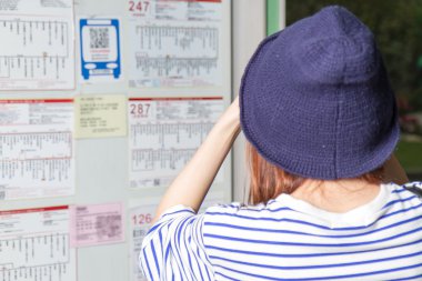 Otobüs durağında Uçus tarifesi arayan kadın