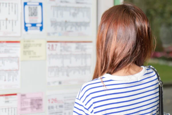 Otobüs durağında Uçus tarifesi arayan kadın