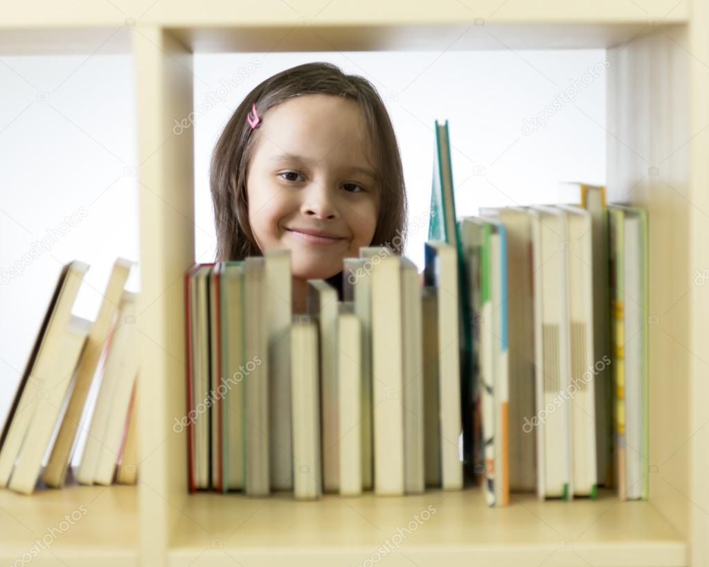 Young Girl Looking At Books On Bookshelf Stock Photo