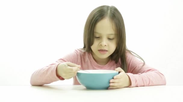 A cute young girl in a pink top eating cereal — Stock Video