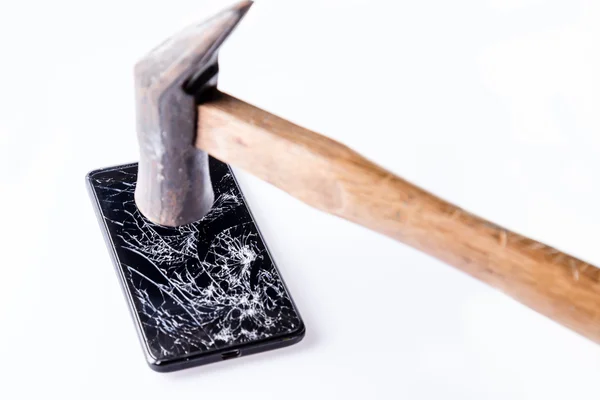 Martillo y smartphone con pantalla rota en blanco . — Foto de Stock