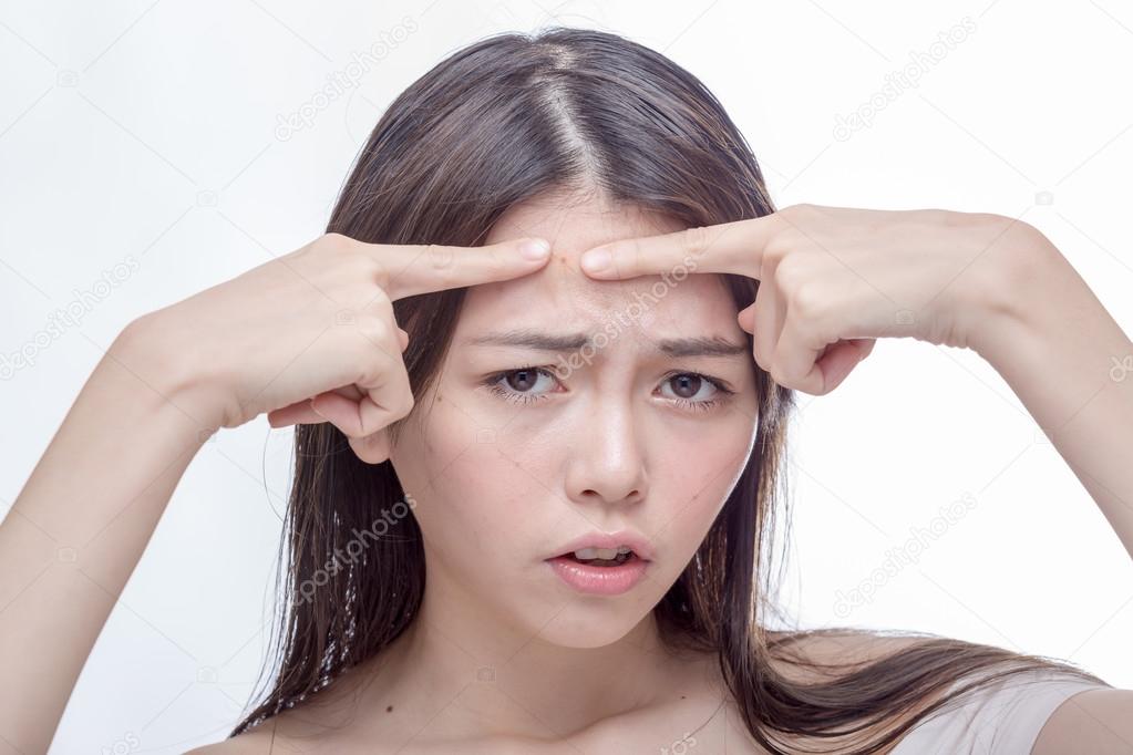 Asian woman squeezing spot on forehead