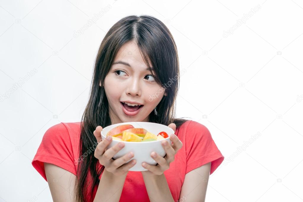 Asian woman holding bowl of fruit
