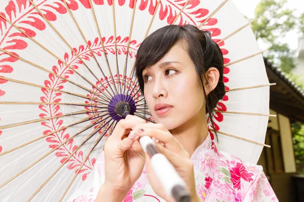 Asian woman in kimono holding umbrella
