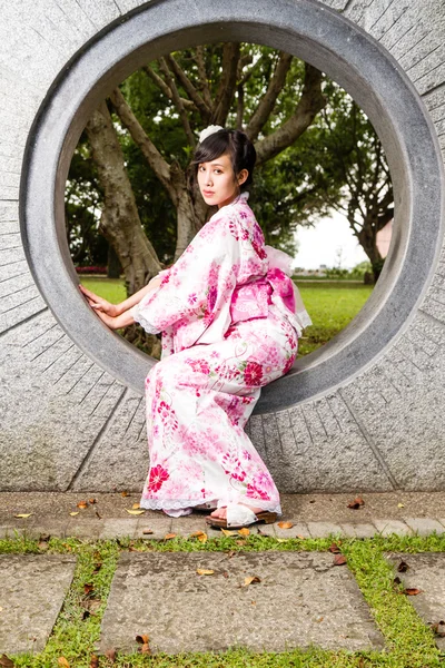 Азіатський жінка в кімоно, сидячи в стіні — стокове фото